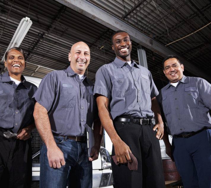 Multi-ethnic workers at trucking facility Multi-ehnic workers in service garage at trucking company.